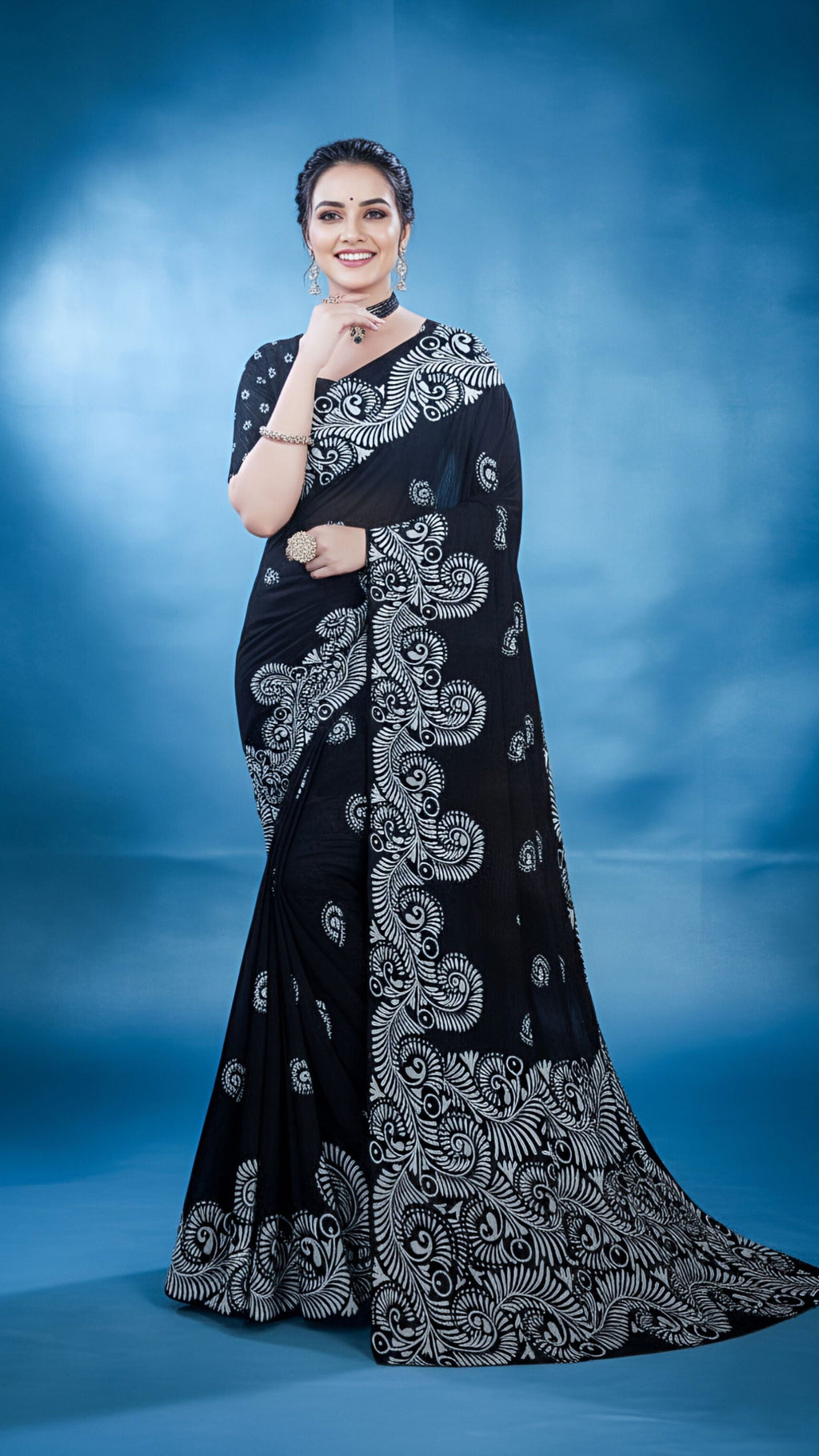 Woman wearing a black saree with white alpona paint, against a light background
