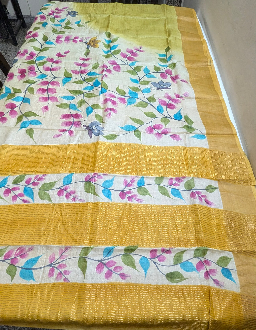 Yellow saree with floral patterns on a bed
